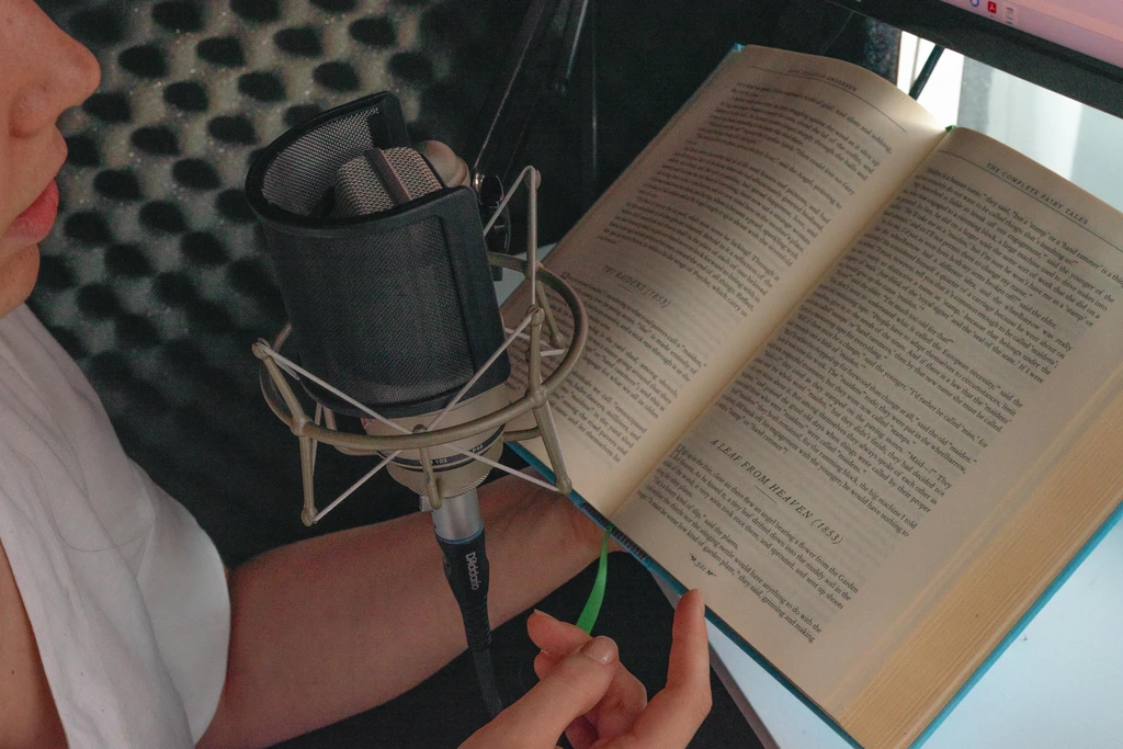 narrator and voice over actress talent narrating a book in a studio vocal booth with condenser mic neumann tlm 103