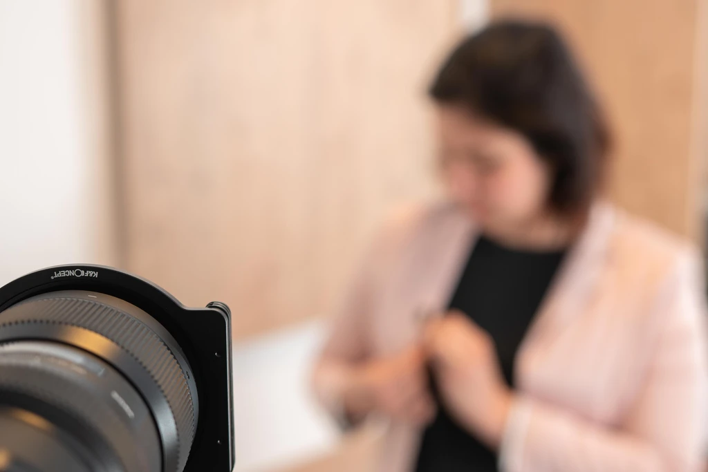 camera man shooting corporate video with a female presenter adjusting microphone