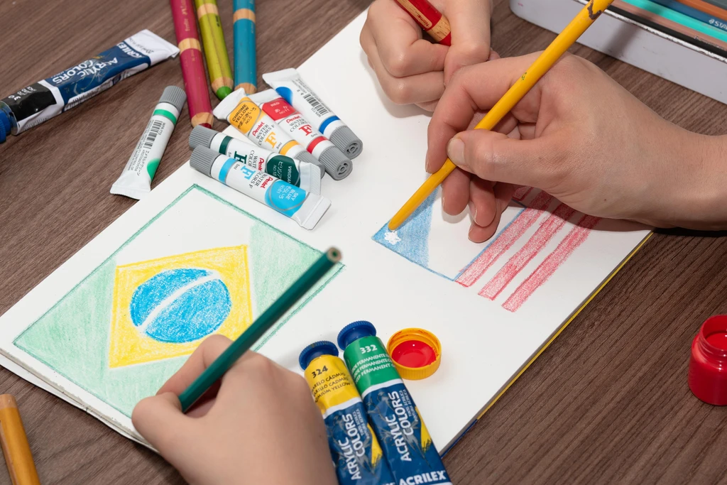 children painting and drawing Brazilian and United States of America flags with pencils and ink